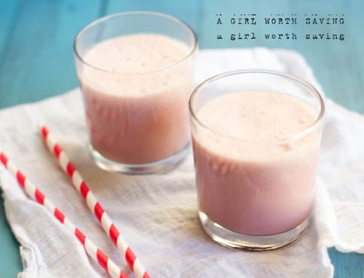 Strawberry Milk in cups on a table with straws nearby