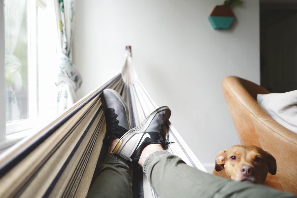 man resting in an indoor hammock  - self care for men