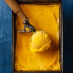 mango ice cream ball in scoop on blue background