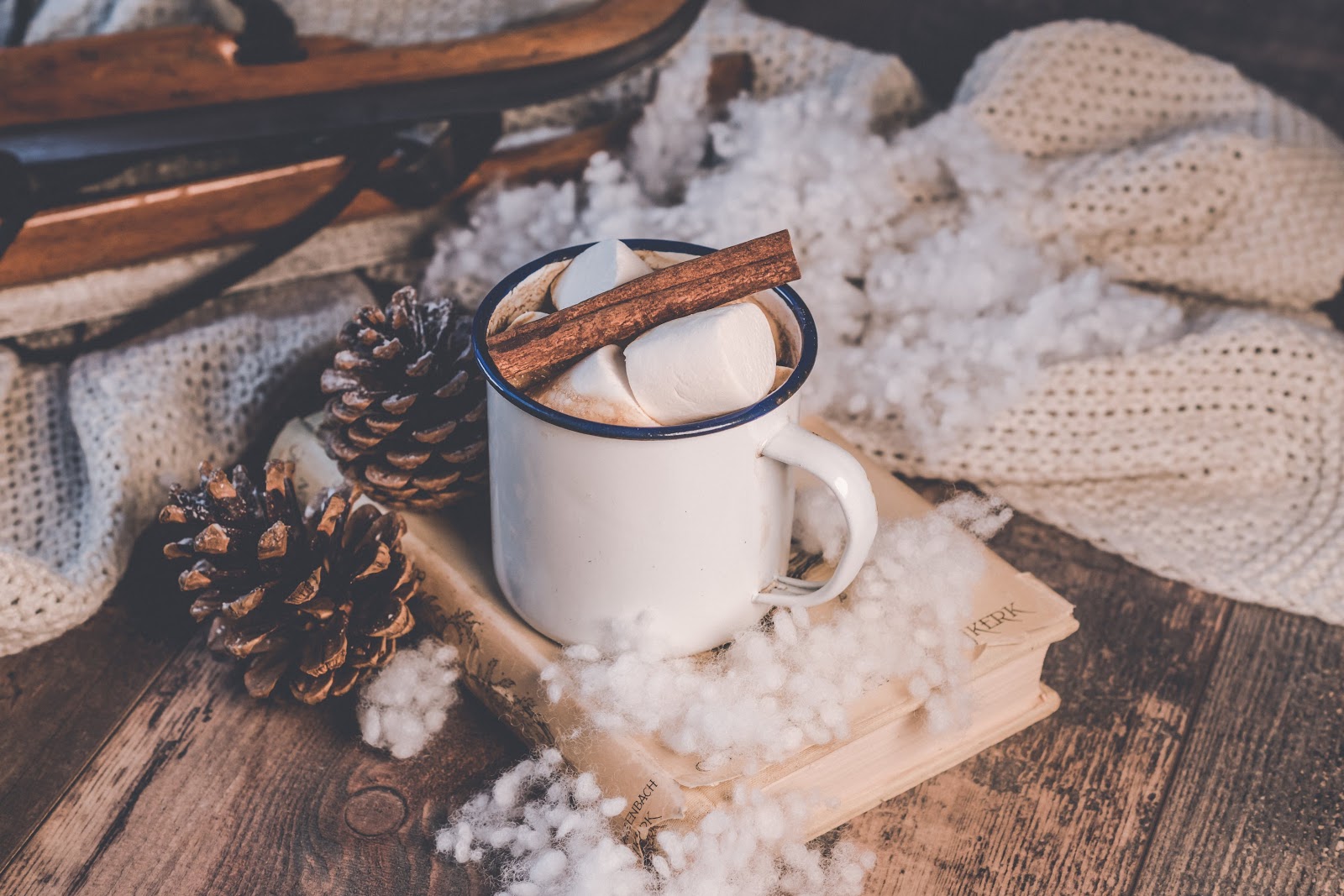 White mug with marshmallows and a cinnamon stick inside