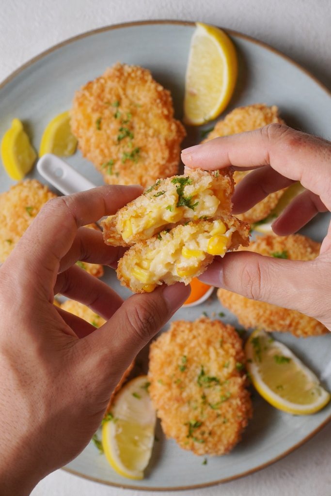 Corn Nuggets on a plate with a woman holding one in her hands