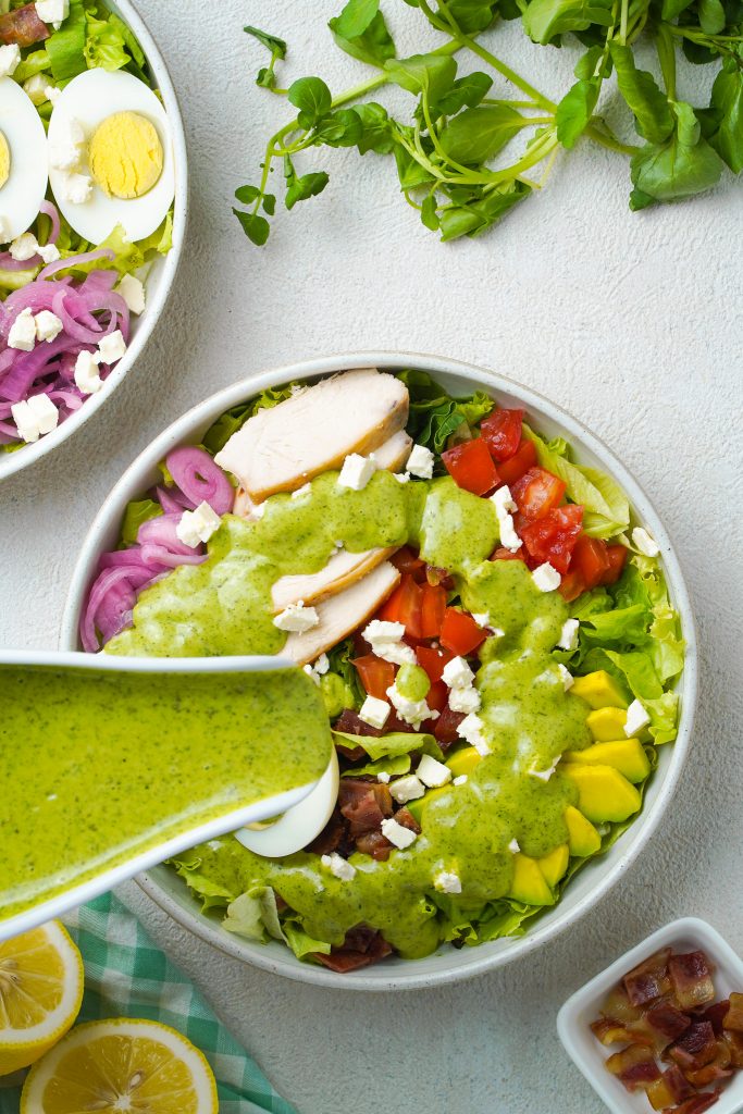 Green Goddess Salad Panera Bread Copycat on table top while covering with salad dressing