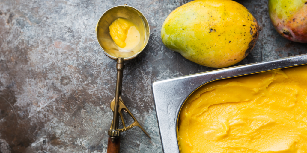 mango ice cream in a pan with fresh mangos 