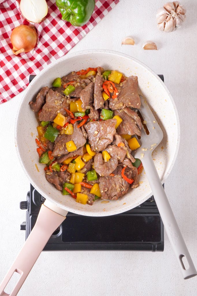 Hunan beef and vegetable mixture cooking together in a saucepan 