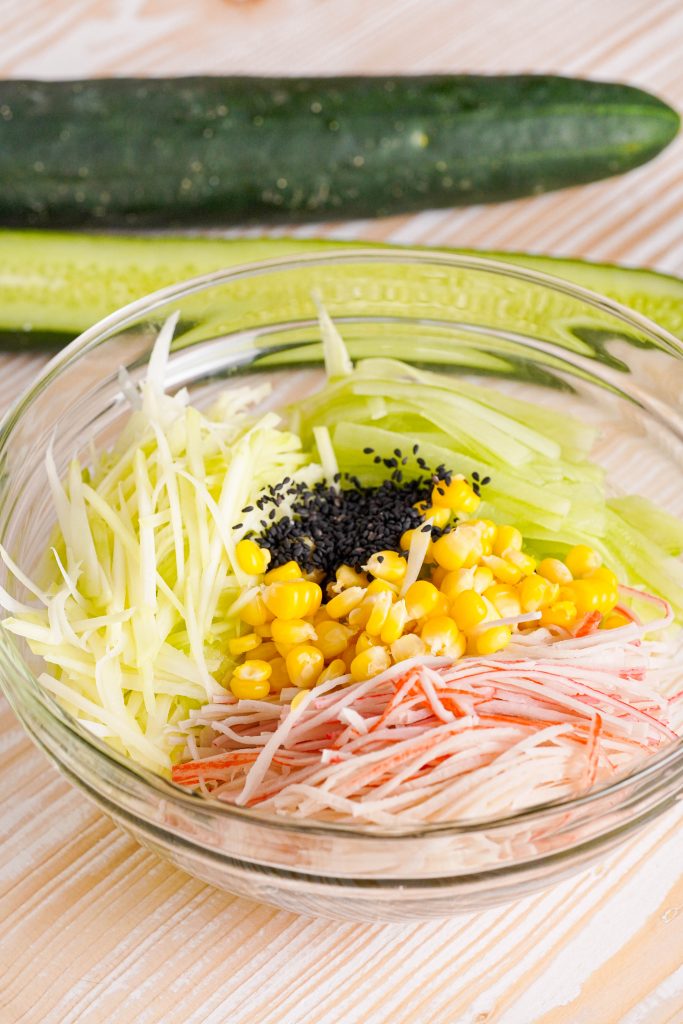 Sliced crab, cucumber, mango and black sesame seeds in a bowl 