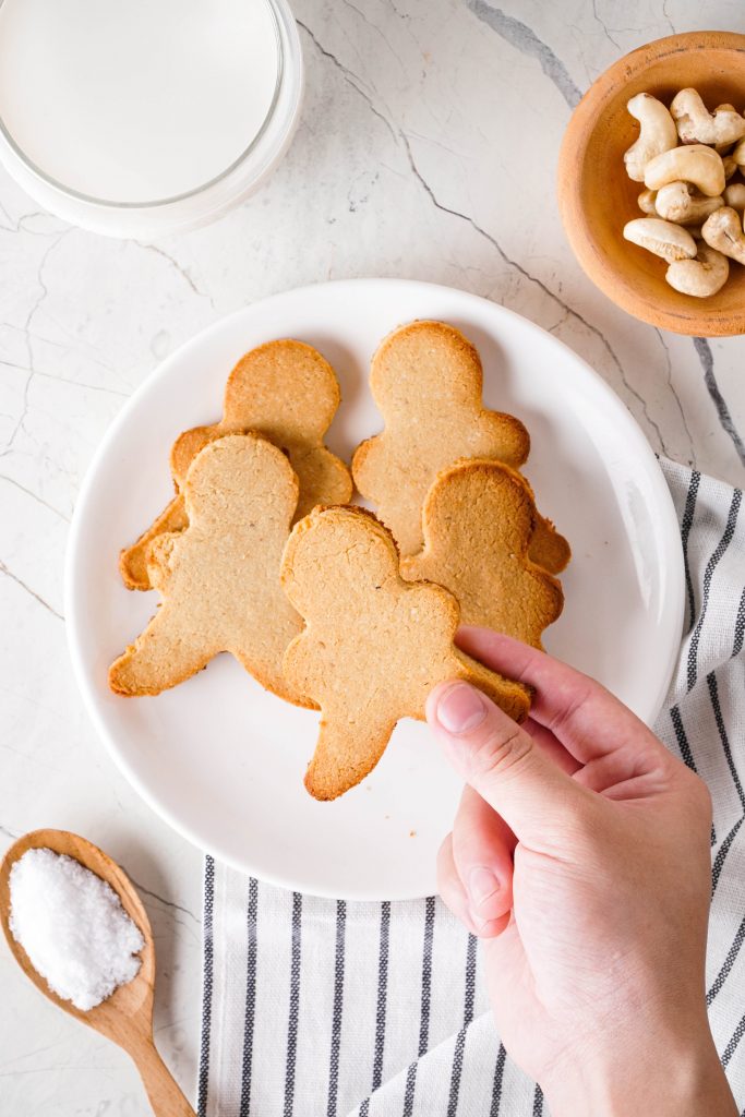 Gluten free sugar cookies on a plate with flour and cashews to the side