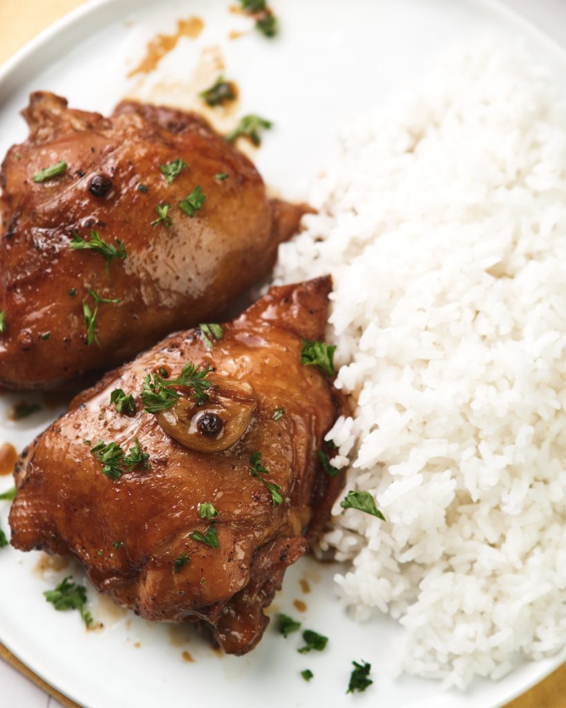 Chicken adobo on a plate with rice on the side 