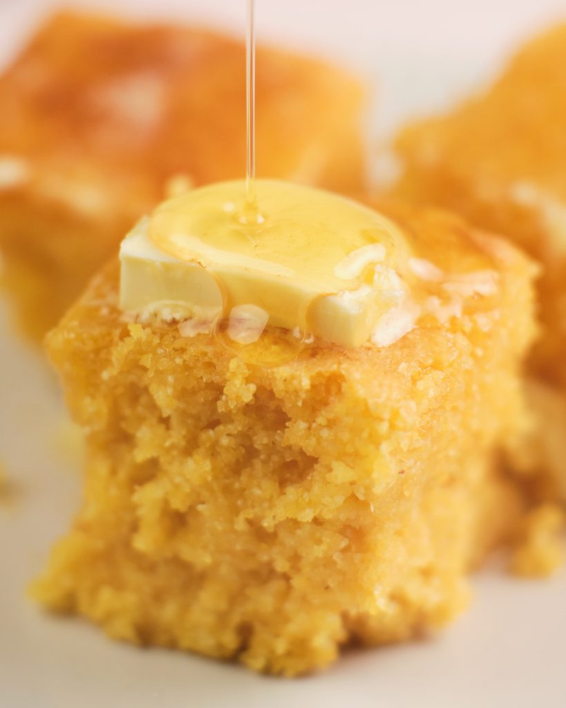 Close up of gluten free cornbread with honey and butter on top