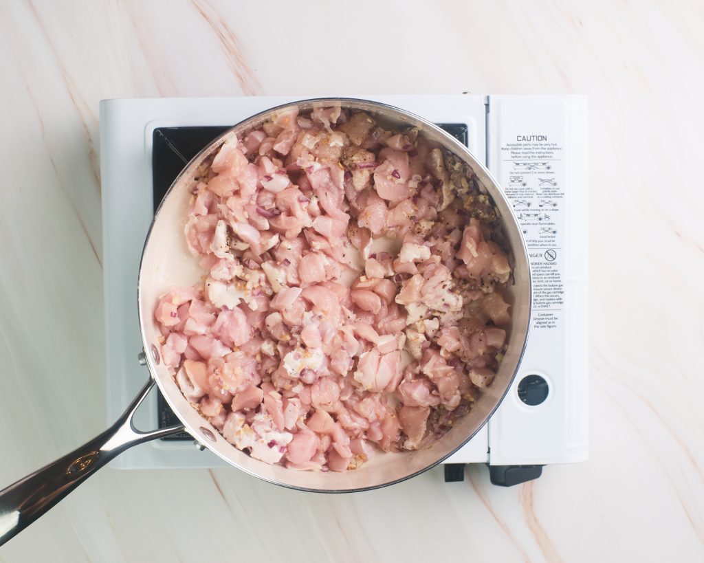 Diced raw chicken cooking in a pan 