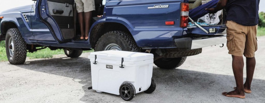 yeti cooler on the ground with a pick up truck in the background