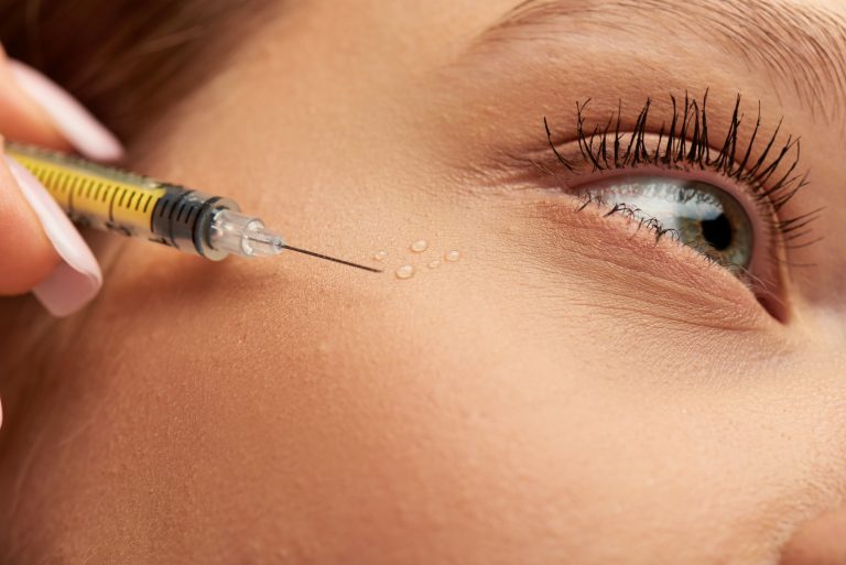 Close-up of a woman's face with a syringe full of collagen