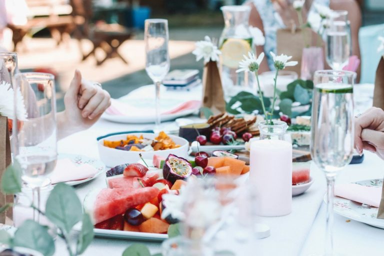 outdoor table with plates of food and glasses of water