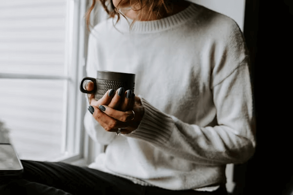 Woman drinking coffee while working on laptop