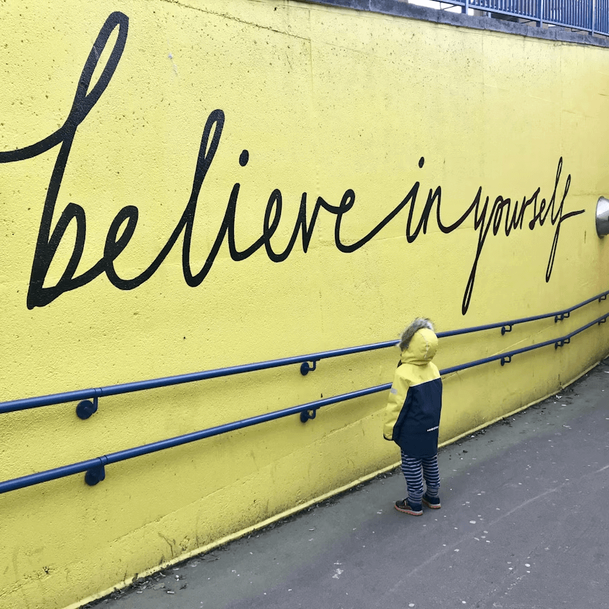 Boy standing against yellow wall