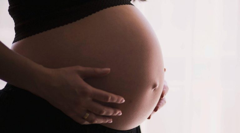Pregnant woman cradling her belly.