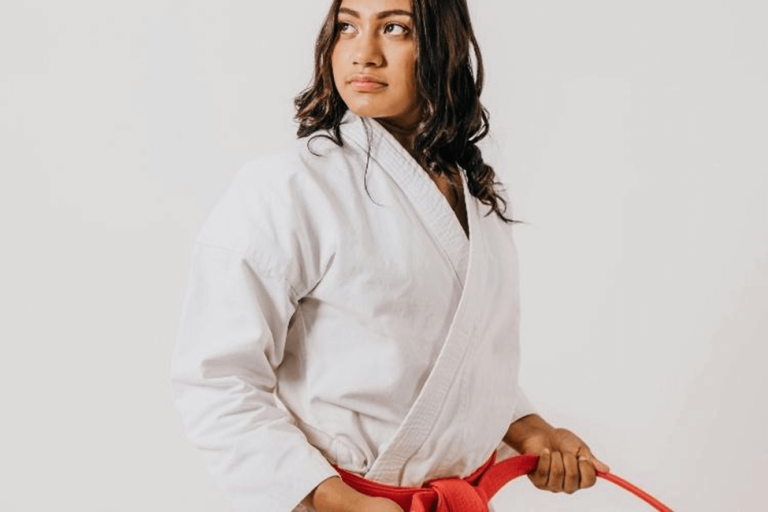 Woman in white kimono practicing Brazilian Jiu-Jitsu holding a red belt