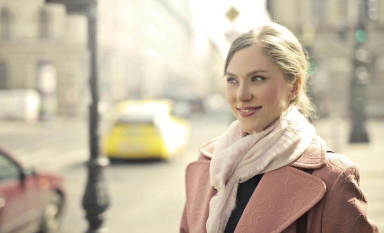 Confident woman smiling on city street.