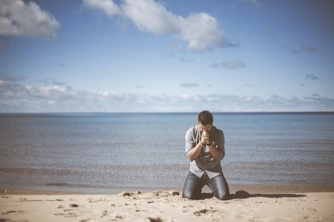 A man with a camera sitting on a beach