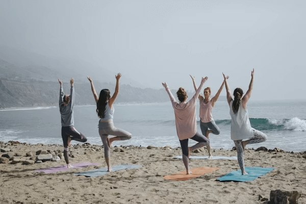 People practicing yoga on beach for wellness
