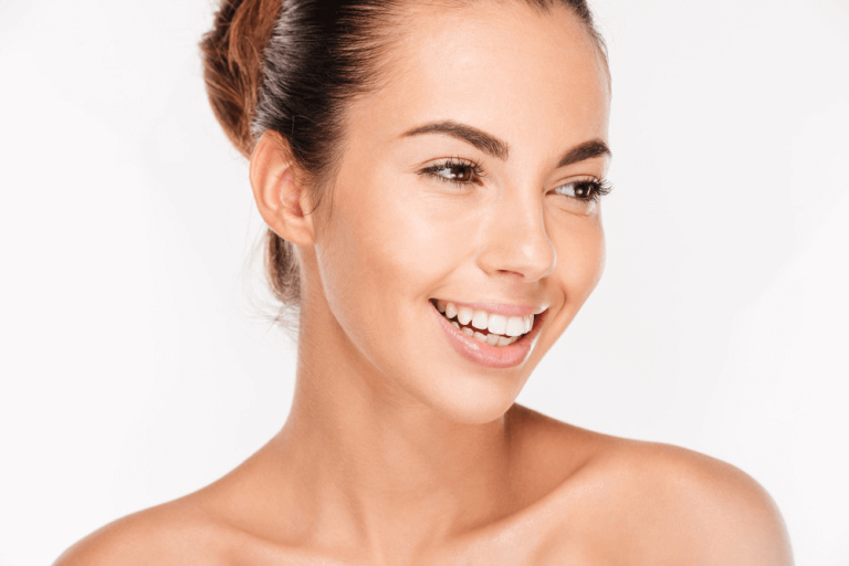 Woman holding toothbrush and smiling for wellness blog