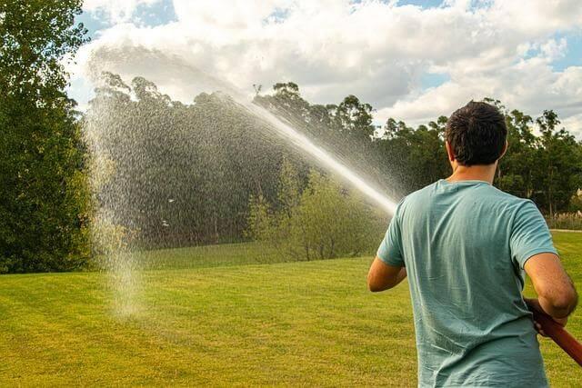 Man watering a field with a hose