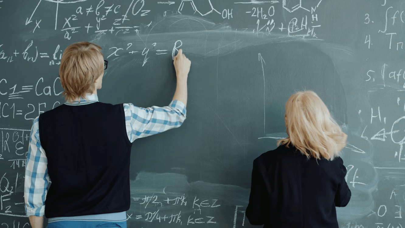 Tutors writing on a blackboard explaining a subject