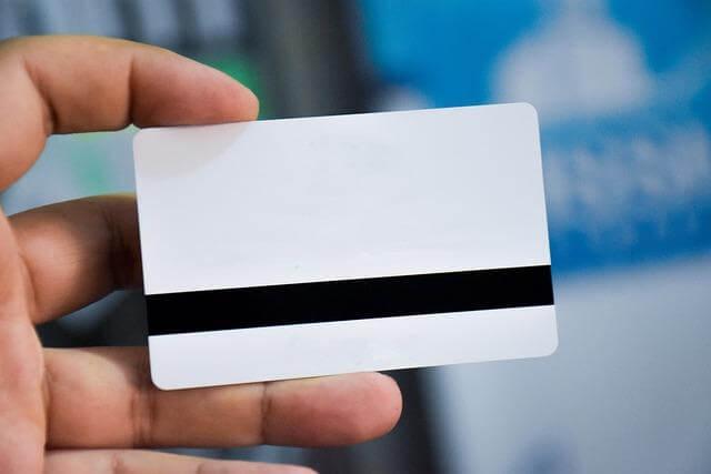 Hand holding a white business card, possibly for contact