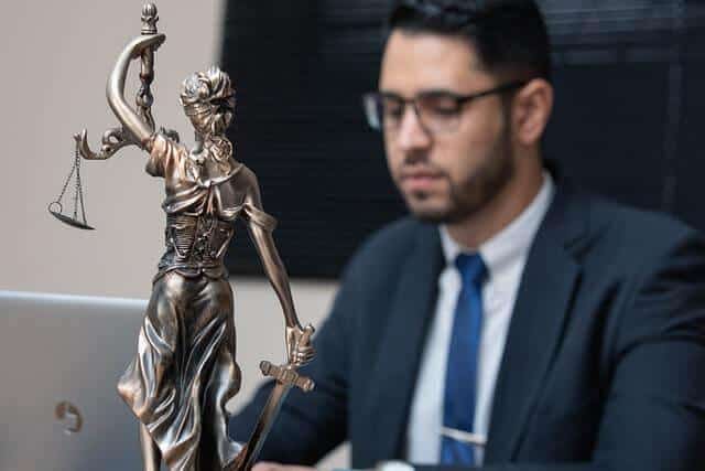 Man at a desk with a Lady Justice statue,