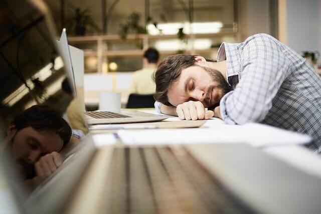 Man sleeping on desk next to laptop