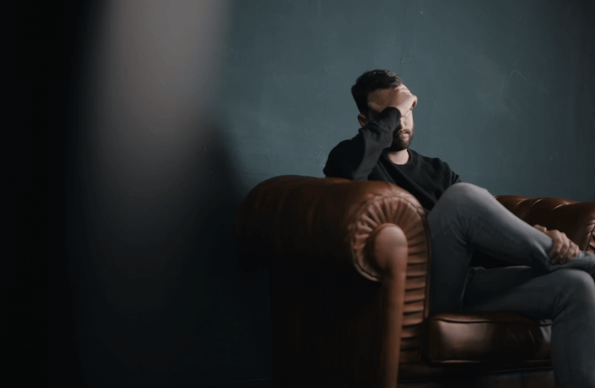 A man sitting on a brown leather couch,