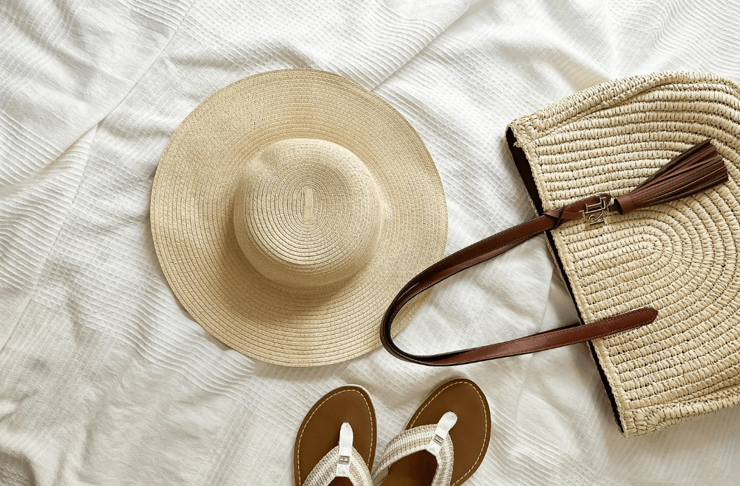 What to Wear in Hot, Humid Climates Kelly Bejelly a pair of sandals and a straw hat on a bed