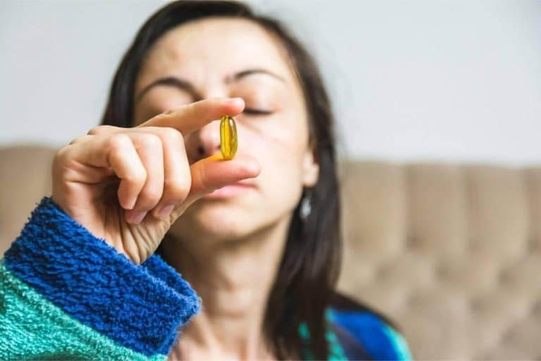A woman holding an omega-3 supplement