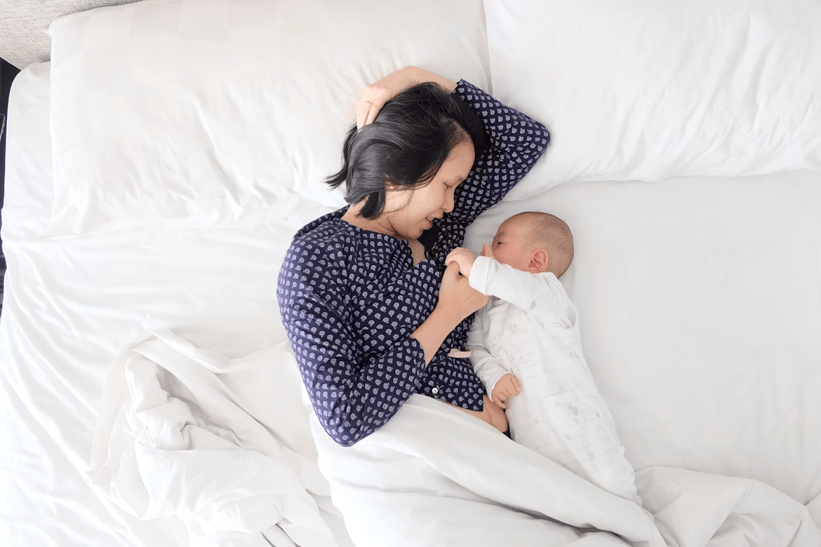A woman lying in bed holding her baby