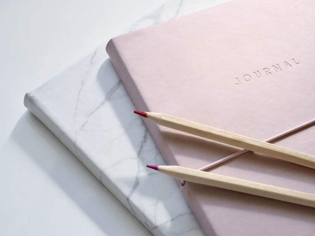 Two pencils on a pink notebook