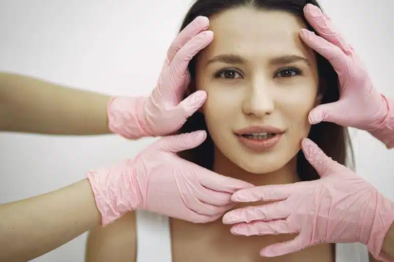Woman with pink gloves covering her eyes