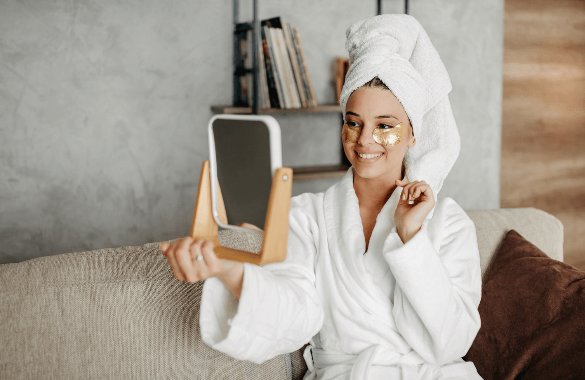 How to Make Your Beauty Routine More Sustainable Kelly Bejelly Woman with towel on head inspecting face in mirror
