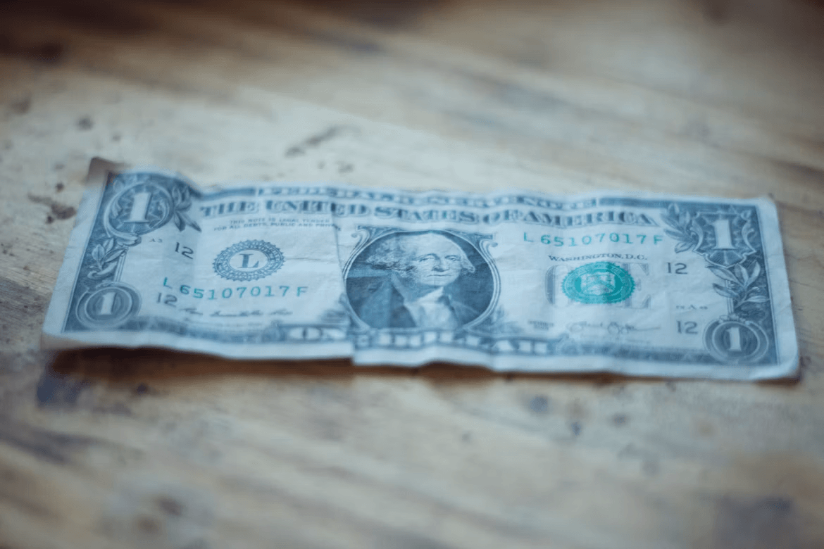One dollar bill on a wooden table, representing