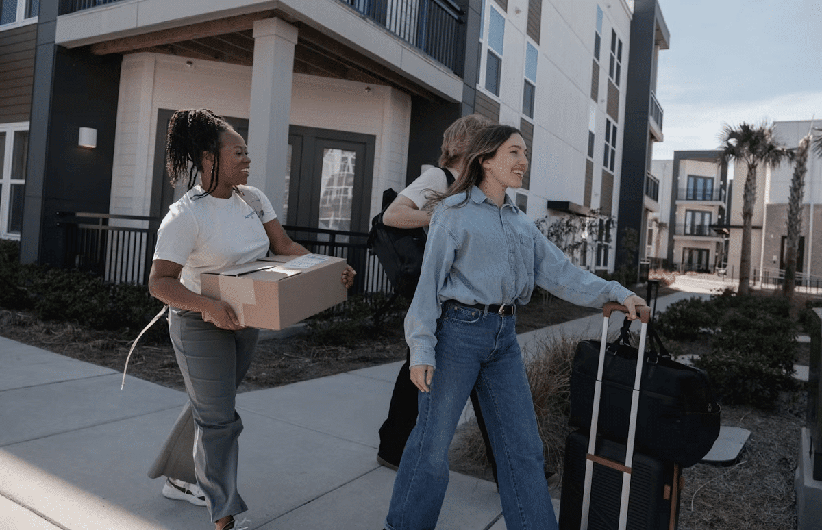Two women with luggage walking on a sidewalk, ready