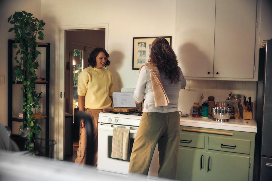 A person holding their lower back while standing in a home kitchen