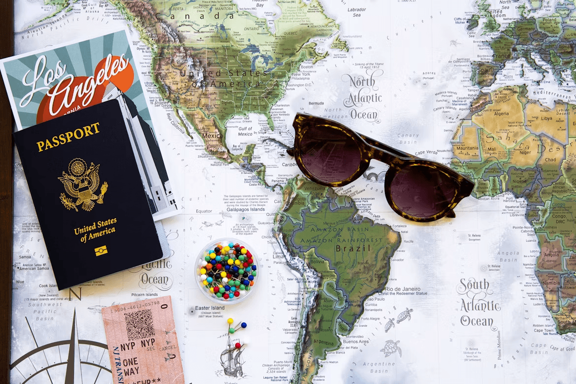 Passport, sunglasses, and candy on a map