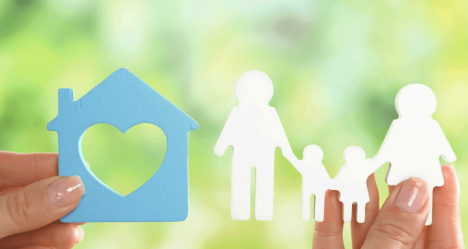 Person holding paper cutout of a house and family,