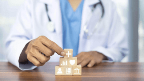 Person in white coat holds wooden block with