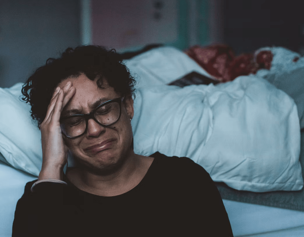 Overwhelmed caregiver sitting on a bed