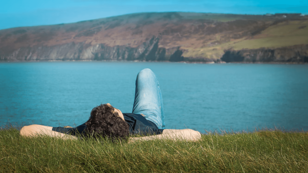 Person relaxing on grass by water