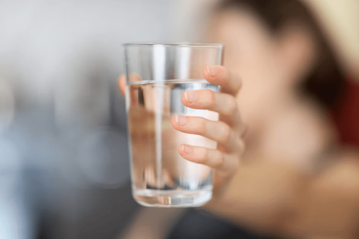 Woman holding a glass of water, symbolizing hydration