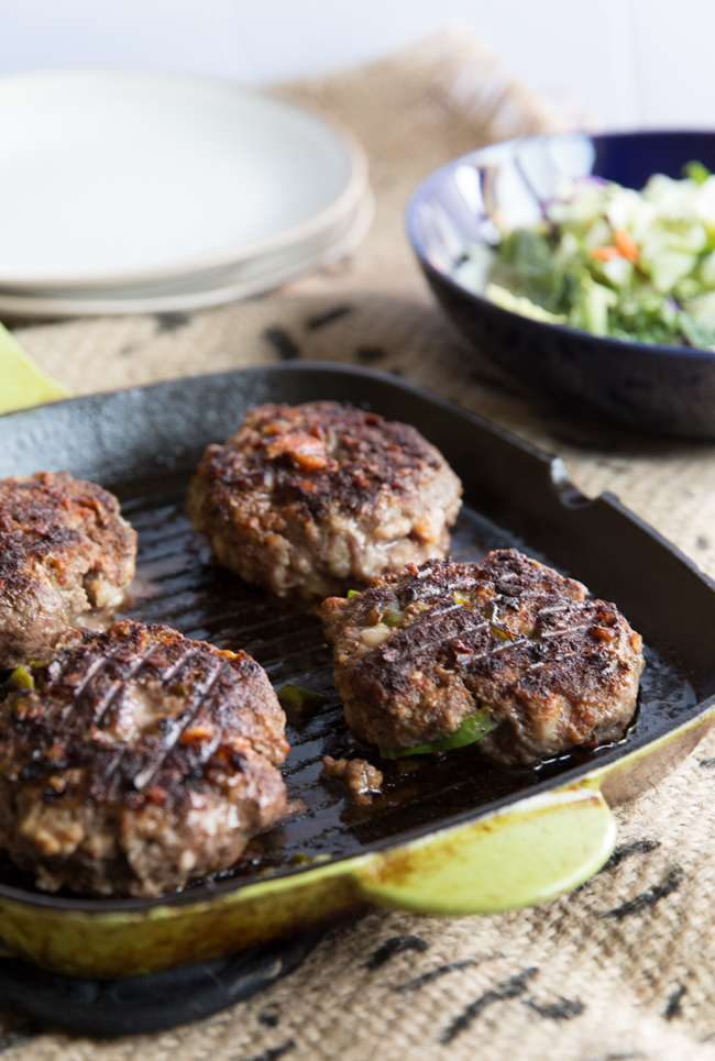 Grilled cowboy burger with side dishes in the background 