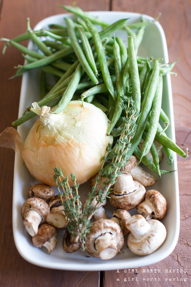 fresh onions, mushrooms, green beans and thyme on a plate to show ingredients for this gluten free green bean casserole